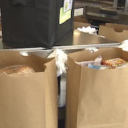 Des sacs en papier remplis d'aliments sur un tourniquet à l'épicerie.