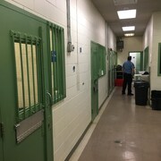 Un agent correctionnel est debout près de deux cellules de détention. 