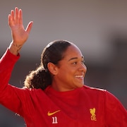 Elle lève la main droite et sourit avant un match.