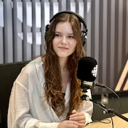 Sophie Grenier est assise dans un studio de radio, avec un casque d'écoute sur la tête.