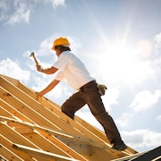 Un ouvrier sur une charpente de toit. 