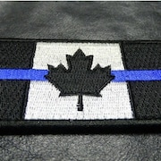 Un drapeau du Canada en noir et blanc est traversé par une mince bande horizontale bleue.