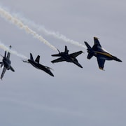 Quatre avions de chasse font de la voltige en groupe.
