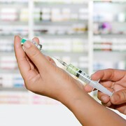 Une personne en tain de préparer une seringue de vaccination.