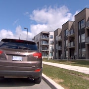 Une voiture immatriculée en Ontario est garée devant un immeuble de logements.