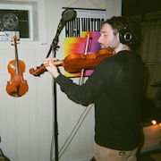 Un homme qui joue du violon dans un studio d'enregistrement.