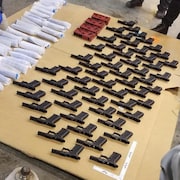 Des pièces d'arme à feu sont alignées sur une table. 