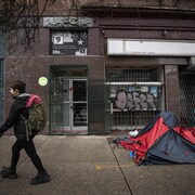 Un passant marche devant une tente dans le quartier Downtown Eastside à Vancouver.