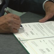 Une personne est entrain de signer un papier officiel.