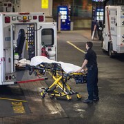 Un ambulancier paramédical tire une civière d'une ambulance. 