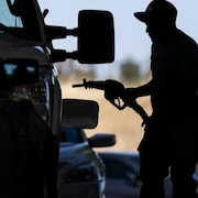 Un homme met de l'essence dans sa voiture. 