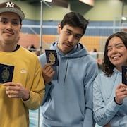 Les trois jeunes tiennent en main leur passeport. 