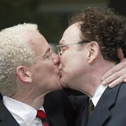 Michael Stark et Michael Leshner s'embrassent, habillés en complet veston-cravate.