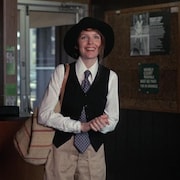 Une femme (Diane Keaton), portant une cravate et un chapeau, sourit.