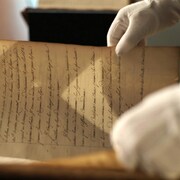 Une personne ouvre un vieux manuscrit datant de l'époque de la Nouvelle-France.