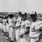 Joueurs et entraîneurs des Expos de Montréal, dont le gérant Gene Mauch (à l'extrême gauche), alignés lors de la présentation du premier match de l'équipe, à domicile, au parc Jarry, à Montréal.