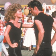 Une jeune fille (Olivia Newton-John) et un jeune homme (John Travolta) habillés tout en noir dansent.