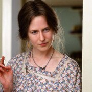 Une femme (Nicole Kidman) en robe fleurie, appuyée contre un cadre de porte fume une cigarette.
