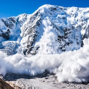 Une montage enneigée où se produit une avalanche.