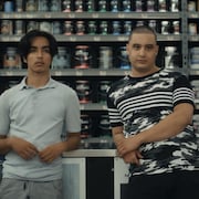 Deux jeunes hommes, adossés au comptoir d'un magasin de peinture.