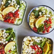 Quatre pots contenant une salade de tortellinis au saumon fumé sur un comptoir gris.
