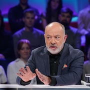 Christian Dubé est assis dans le studio.