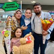 Une photo du jeune Adnan Kharsa avec ses parents et sa jeune soeur Sham qui tient un bouquet de fleurs et un ours en peluche, à côté du logo "Bonne nouvelle" de MAJ.