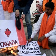 Un homme met le feu à un drapeau canadien.