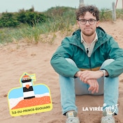 Un jeune homme qui porte des lunettes est assis sur une plage, à côté d’une illustration d’un phare avec un cœur et le titre « La virée MAJ ».