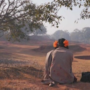 Une fille assise dans un paysage indien est vue de dos.