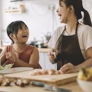 Une maman et sa fille, d'origine asiatiques, cuisinent en riant