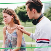 Le garçon met sa main sur l'épaule de la fille, qui semble mal à l'aise. 