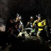Quatre personnes mangent un repas dans la grotte.
