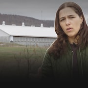La journaliste Julia Pagé devant une porcherie.