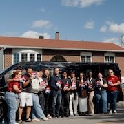 Des jeunes militants pour le Parti lib&eacute;ral du Qu&eacute;bec devant un autobus.