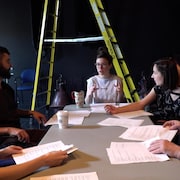 Des gens de théâtre discutent du scénario d'une pièce.