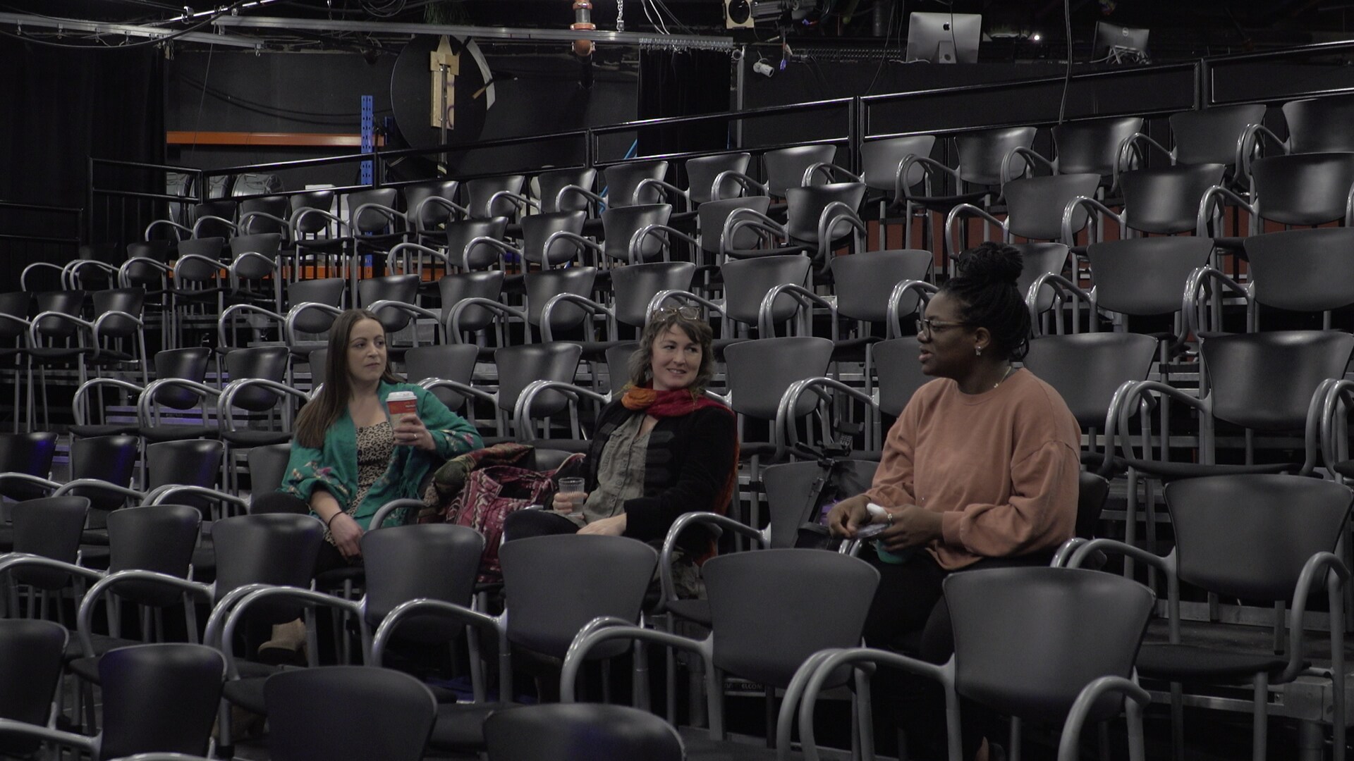 Les chanteuses Flora Luna, Véronique Trudel et Priscila Bieni assises dans une salle de spectacle vide lors d'une pause des répétitions du Chant'Ouest.