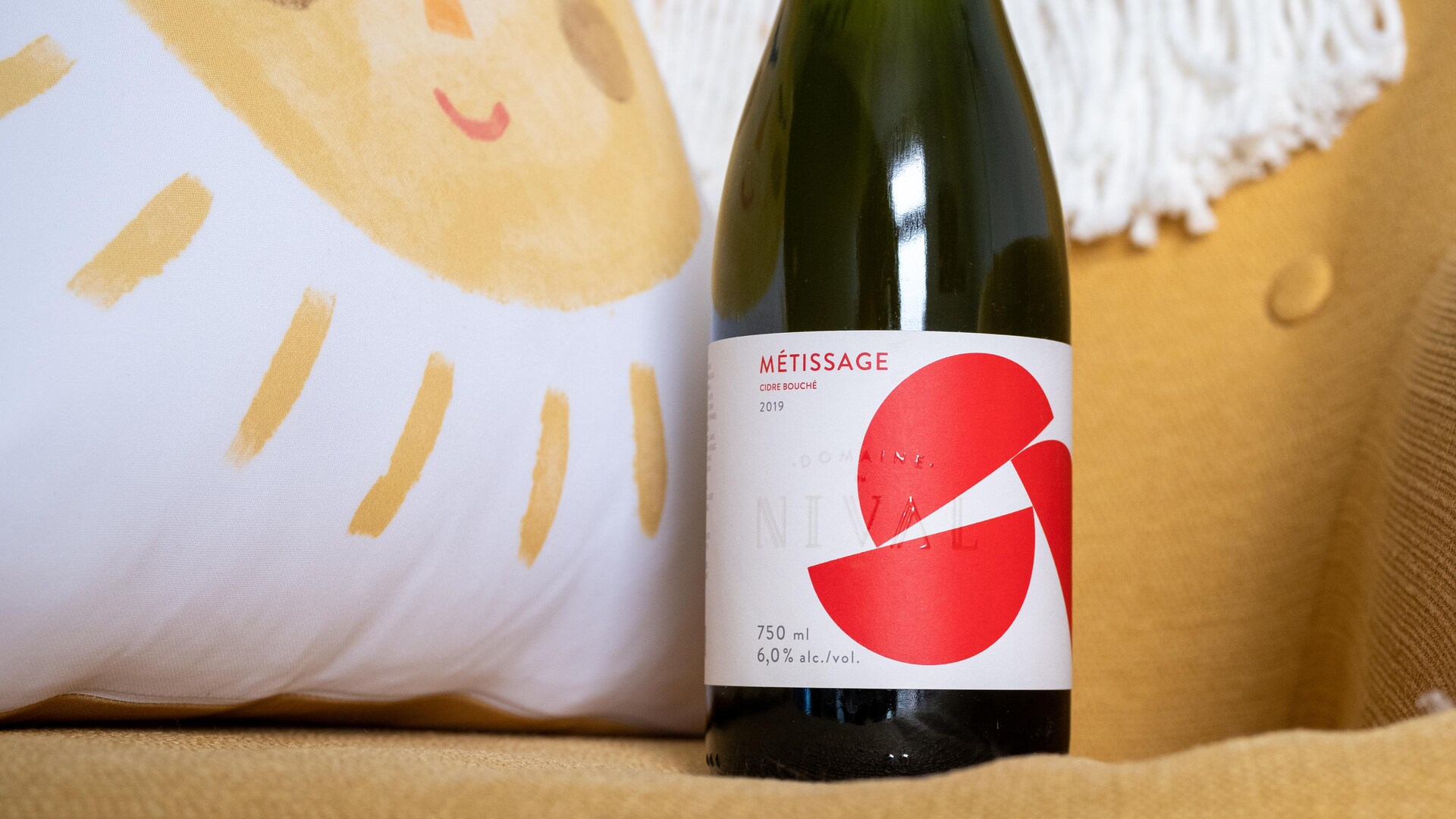 Une bouteille de cidre à côté d'un coussin avec un soleil jaune. Une bouteille de cidre à côté d'un coussin avec un soleil jaune.
