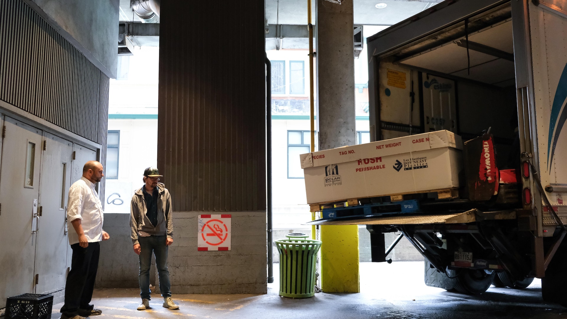 Deux hommes dans un entrepôt attendent un camion de livraison Deux hommes dans un entrepôt attendent un camion de livraison