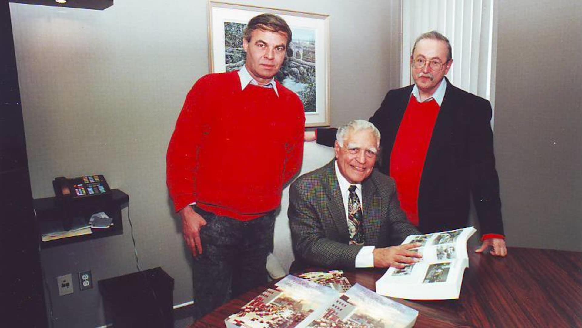 Three men smile for a photo with a big book in his hands. Three men smile for a photo with a big book in his hands. death valdorian journalist author denys