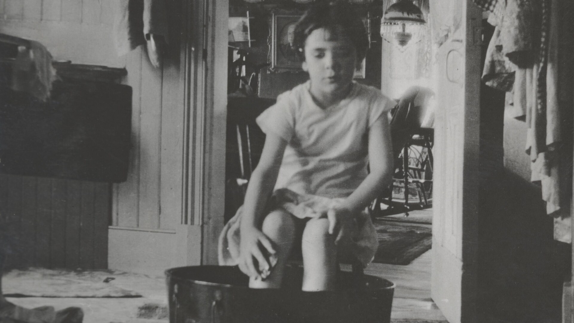 Enfant faisant sa toilette dans une cuvette, dans une maison modeste du début du siècle. 