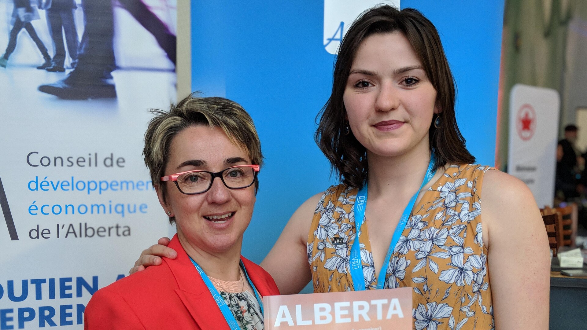 Deux femmes posent devant une affiche. Deux femmes posent devant une affiche.