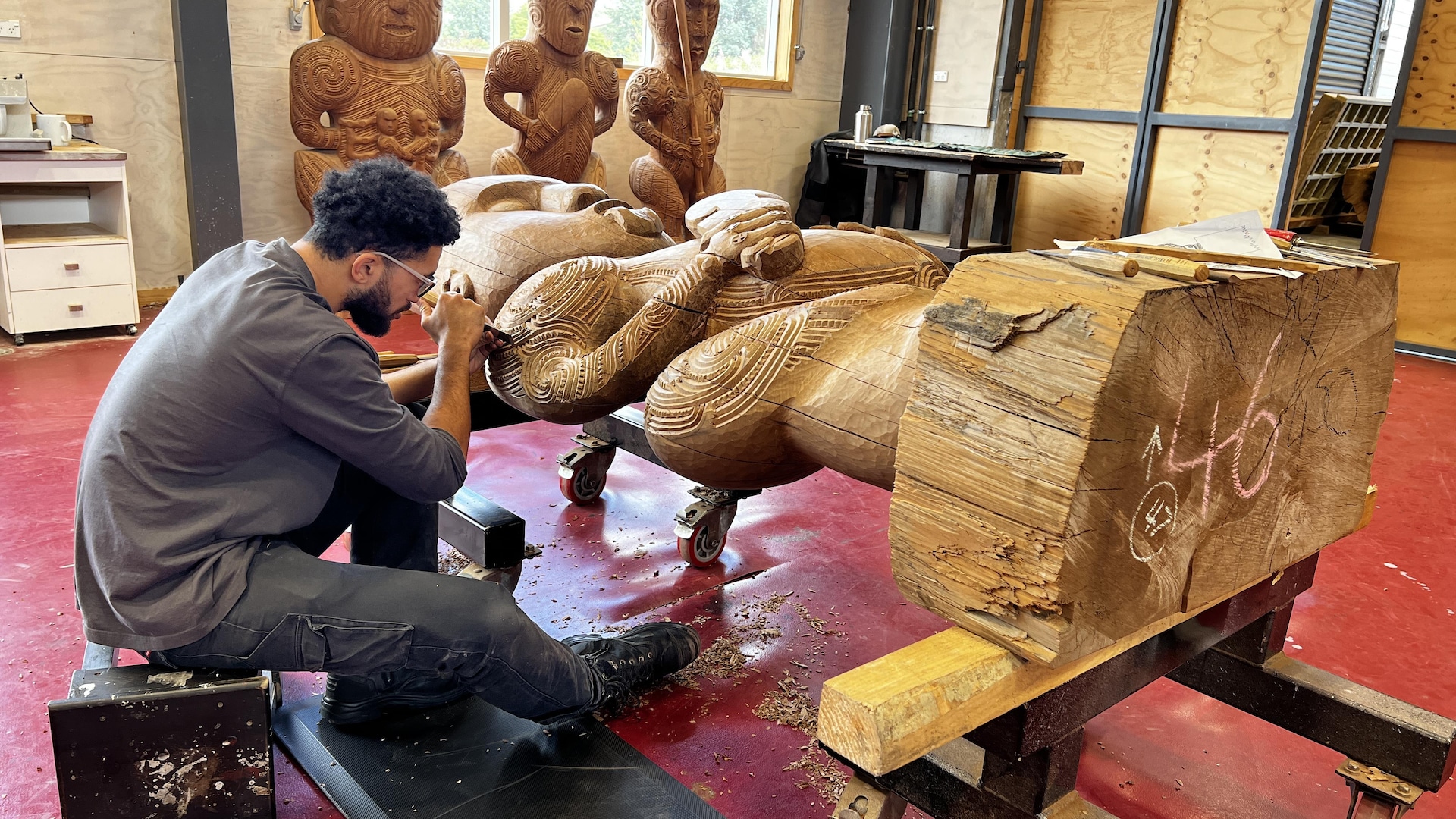 Craftsman working on a large wooden statue. 