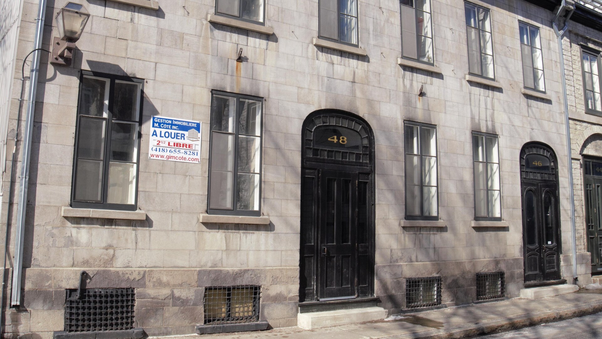 La porte foncée surmontée d'un cintre vitré, les lucarnes du toit de tôle et la fenestration classique d'une maison de pierres attirent l'attention sur la rue Sainte-Geneviève. La porte foncée surmontée d'un cintre vitré, les lucarnes du toit de tôle et la fenestration classique d'une maison de pierres attirent l'attention sur la rue Sainte-Geneviève.