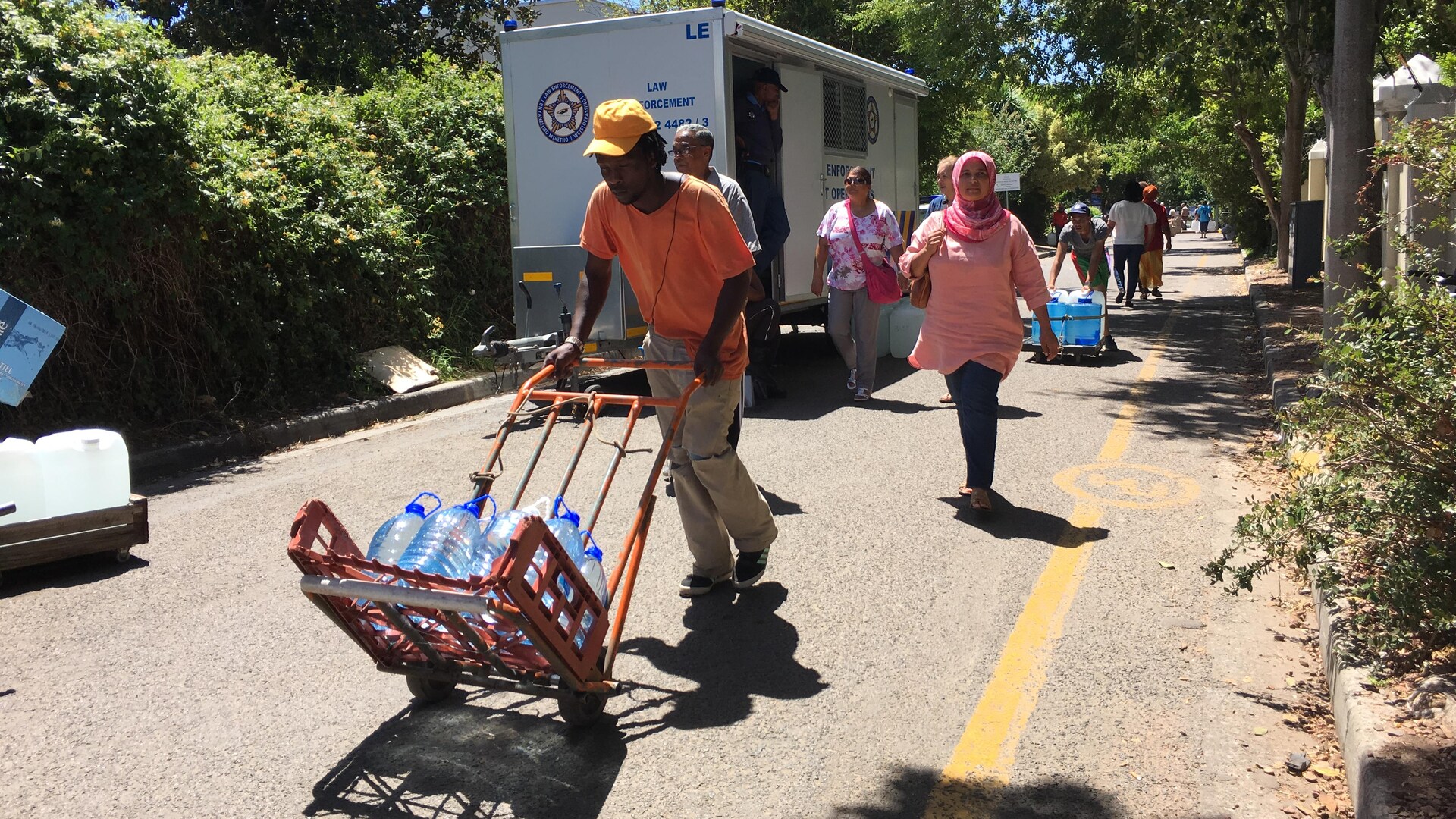 Des gens transportent des bidons d'eau dans des charriots.