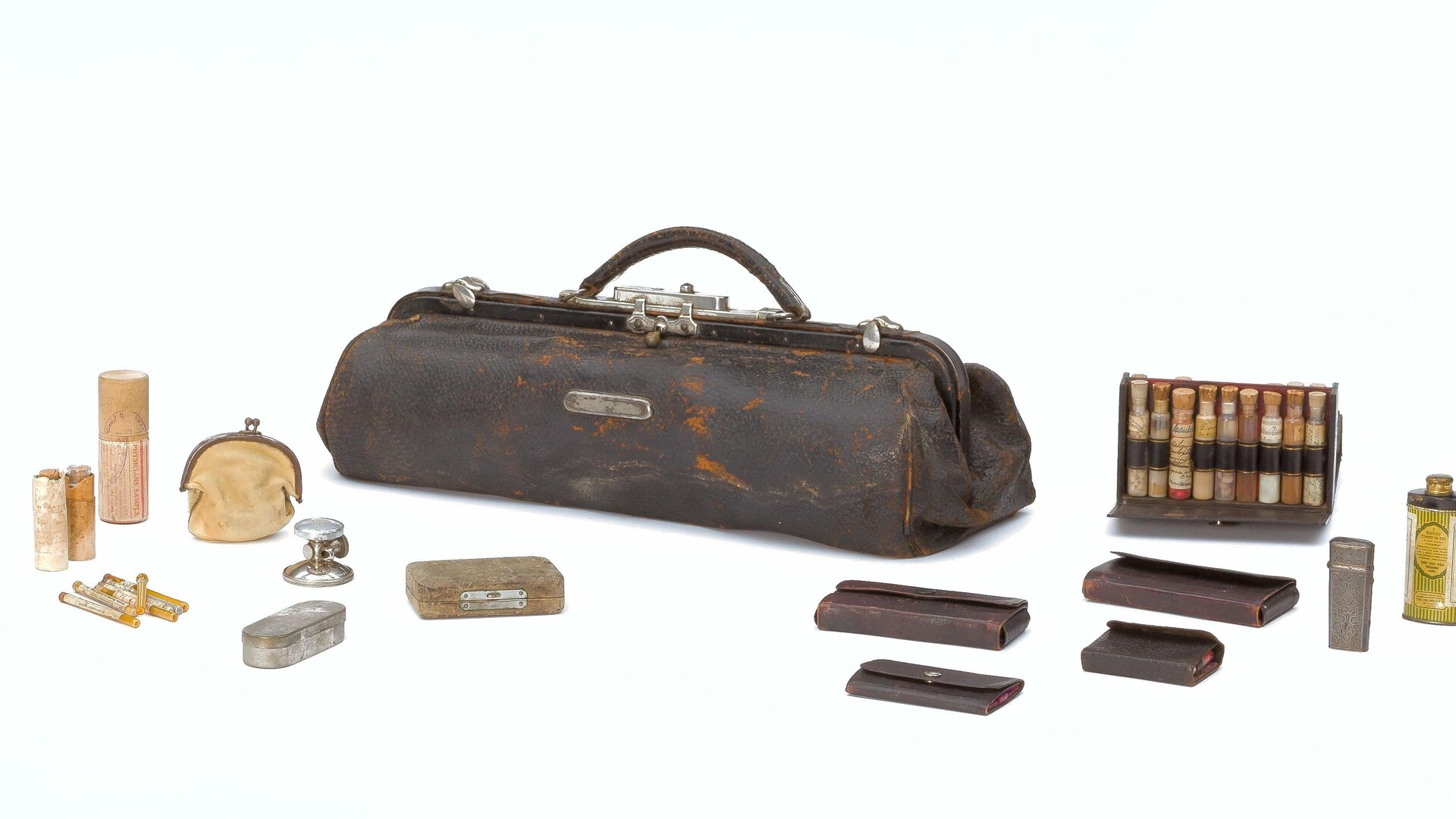 On voit la trousse complète d'un médecin autour de sa mallette de cuir: des fioles en abondance et plusieurs petits étuis de cuir contenant probablement des seringues et autres accessoires. On voit la trousse complète d'un médecin autour de sa mallette de cuir: des fioles en abondance et plusieurs petits étuis de cuir contenant probablement des seringues et autres accessoires.