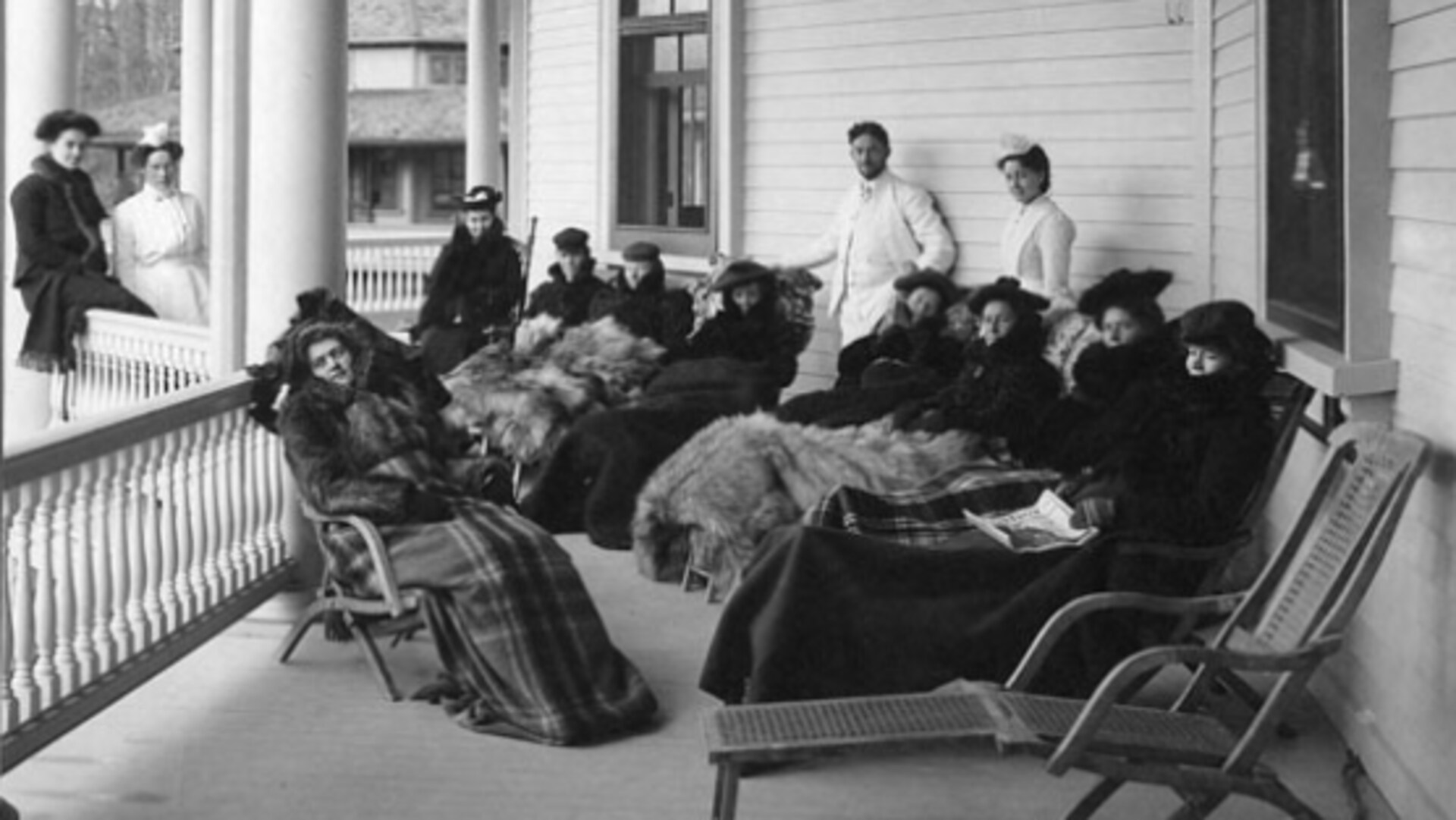 Des patients en cure soigneusement emmitouflés dans de luxueuses fourrures prennent de l'air sur la galerie d'un vaste cottage. Des patients en cure soigneusement emmitouflés dans de luxueuses fourrures prennent de l'air sur la galerie d'un vaste cottage.
