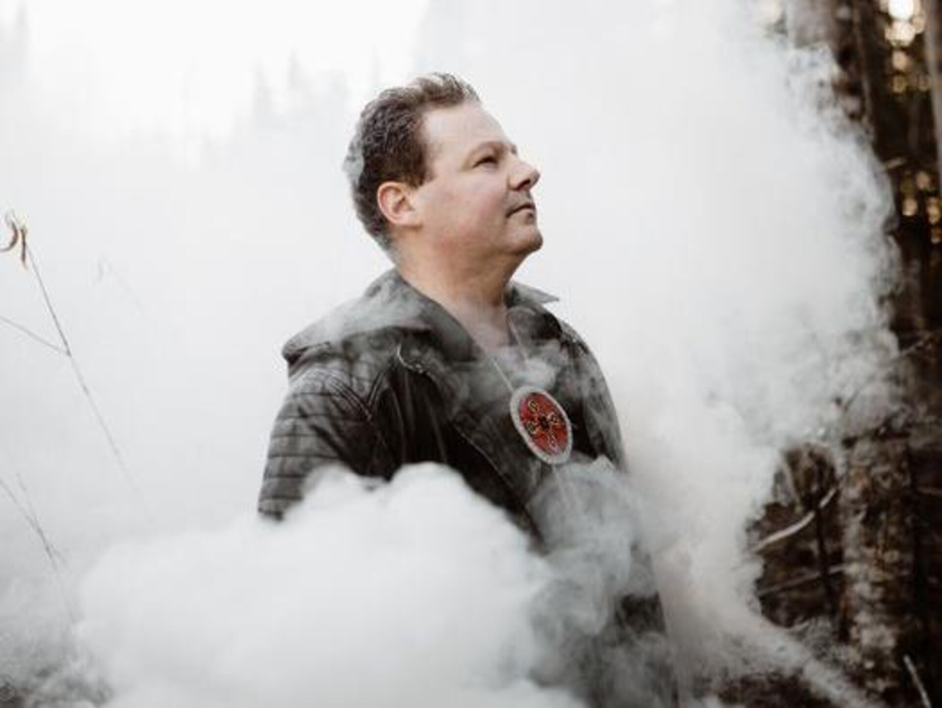 Portrait de Mike Paul de profil dans un paysage entouré de fumée.