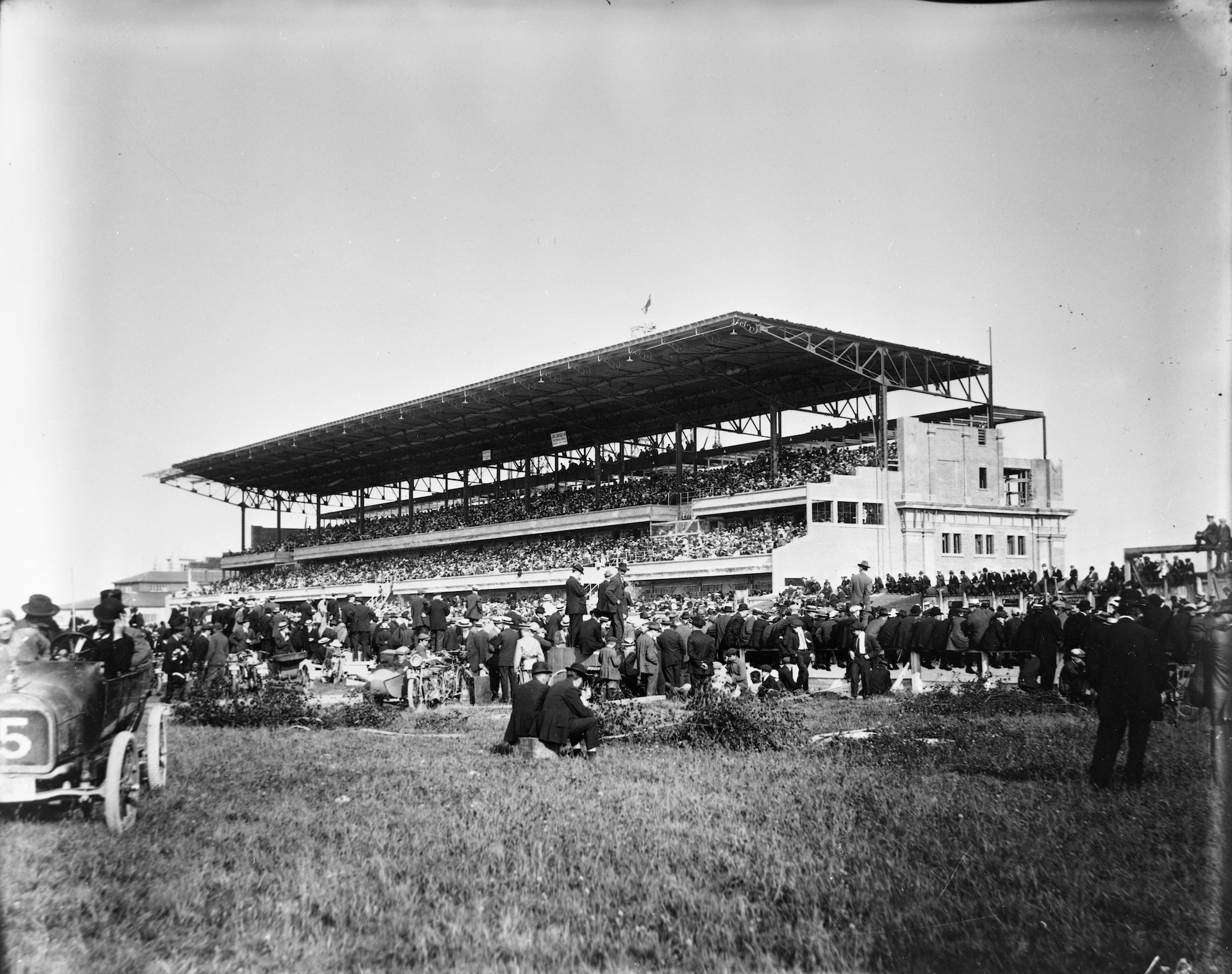 L'hippodrome tel qu'on peut le voir durant les années 1920, avec sa foule des beaux jours. La foule, compacte, est impressionnante. On y fait courir les chevaux, mais on peut voir une voiture de course au premier plan. L'hippodrome tel qu'on peut le voir durant les années 1920, avec sa foule des beaux jours. La foule, compacte, est impressionnante. On y fait courir les chevaux, mais on peut voir une voiture de course au premier plan.