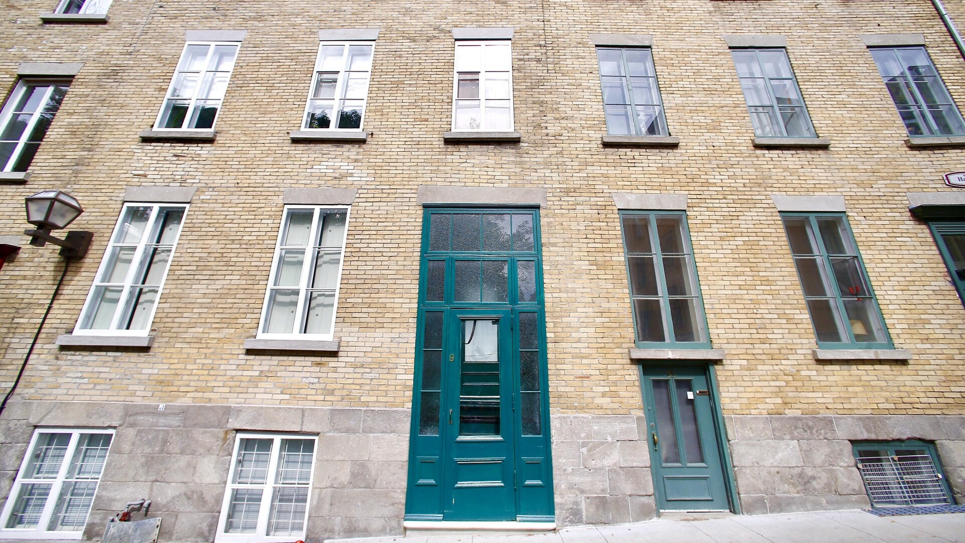 Une façade à la fenestration impressionnante montre l'influence britannique d'un autre secteur du Vieux-Québec avec sa porte d'entrée fenestrée donnant directement sur un escalier intérieur. Une façade à la fenestration impressionnante montre l'influence britannique d'un autre secteur du Vieux-Québec avec sa porte d'entrée fenestrée donnant directement sur un escalier intérieur.